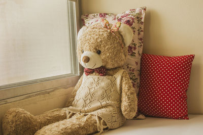 Teddy bear sits lonely by the window.