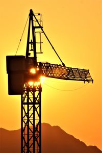 Low angle view of crane against sky during sunset