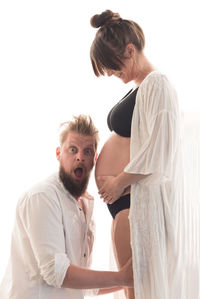 Young couple standing against white wall