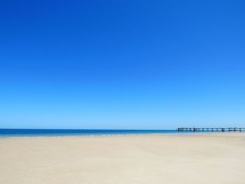 Scenic view of beach against clear blue sky