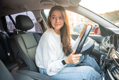 Young woman using mobile phone while sitting in car