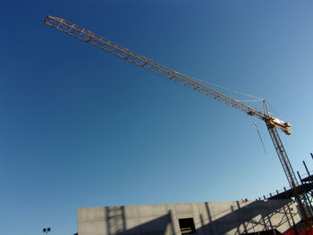 Low angle view of crane against clear blue sky