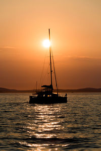 Silhouette sailboat on sea against sky during sunset