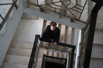 Low angle view of young man standing on steps at home