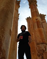 Low angle view of young man standing against sky