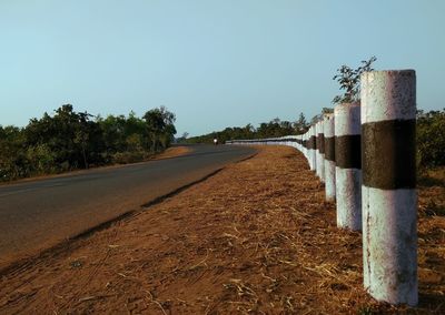 View of road by trees against clear blue sky