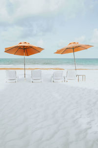 Deck chairs on beach against sky