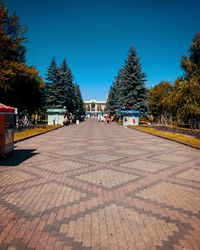 Footpath in city against blue sky