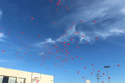 Low angle view of balloons flying against blue sky