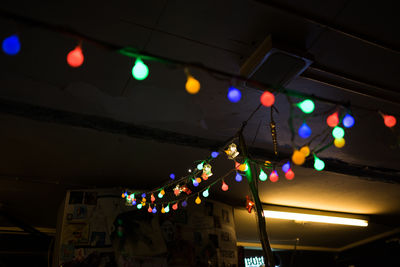 Low angle view of illuminated light bulbs hanging from ceiling