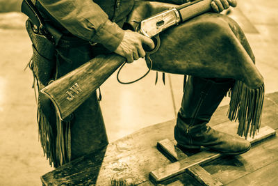 Low section of man with rifle over cross