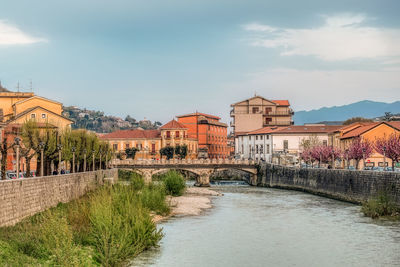 Buildings by river against sky
