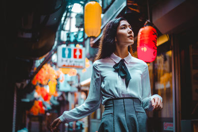 Young woman looking away while standing in city