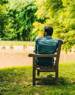 Rear view of man sitting on wooden bench