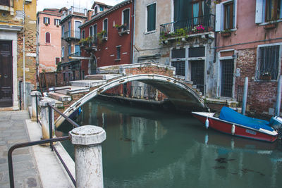 Boats moored on canal amidst buildings in city