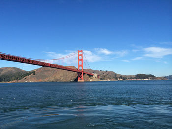 Golden gate bridge over mountain against blue sky