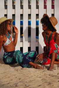 Two young black women having conversation at the beach smiling