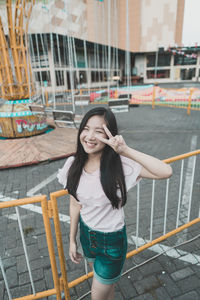 Portrait of smiling young woman standing against railing