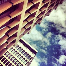 Low angle view of modern building against cloudy sky