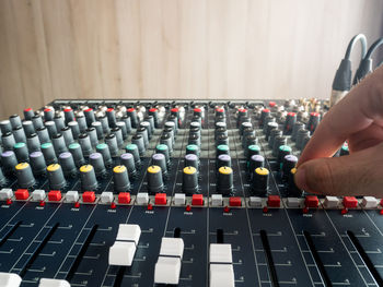 Cropped hand of male dj playing music on sound mixer against wall