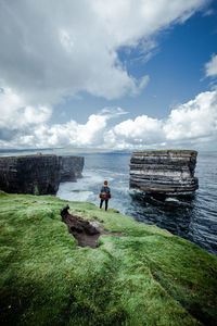 People on rocks by sea against sky