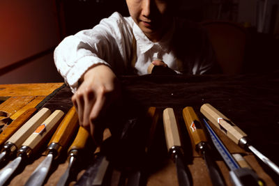 Young chinese woman violin maker is choosing suitable tools for making the violin in her workshop