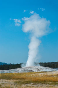 Steam emitting from hot spring against sky