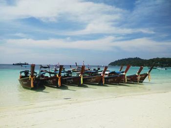 Deck chairs on beach against sky