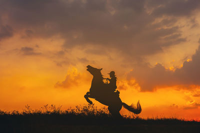 Silhouette man standing on field against sky during sunset