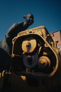 Low angle view of old machine part against clear blue sky