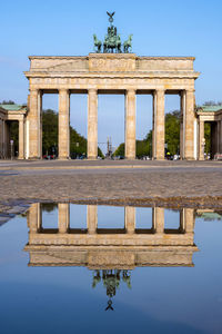 The famous brandenburger tor in berlin with no people reflected in a puddle