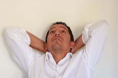 Portrait of young man lying on white wall