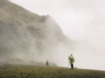 Rear view of man standing on mountain against sky
