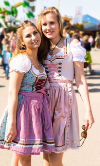 Portrait of smiling young female friends standing at amusement park