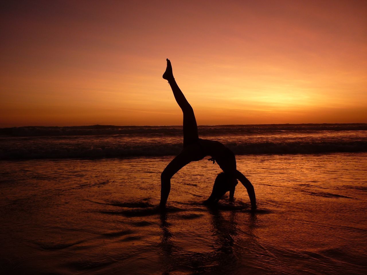 sunset, silhouette, sea, balance, orange color, beach, nature, beauty in nature, tranquil scene, healthy lifestyle, strength, real people, exercising, sun, scenics, sky, water, outdoors, sand, horizon over water, flexibility, one person, adult, people