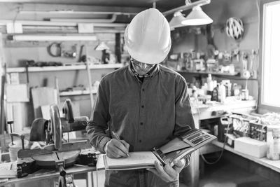 Man writing in book at workshop