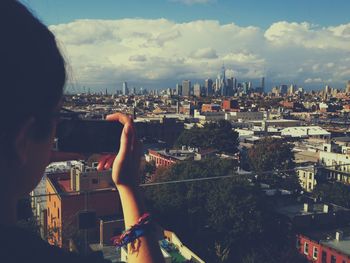 Woman photographing manhattan against sky