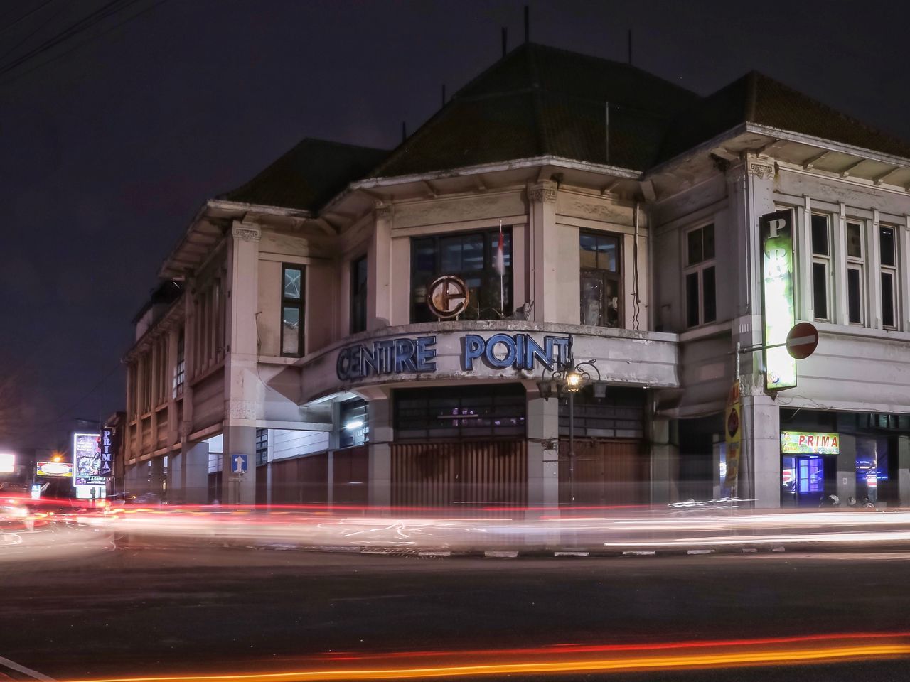 LIGHT TRAILS ON STREET AGAINST BUILDINGS AT NIGHT