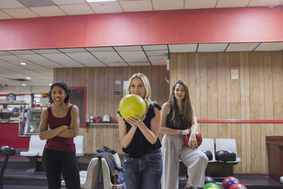 A young woman bowling with friends.