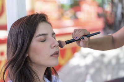 Cropped hand of woman applying make up to client