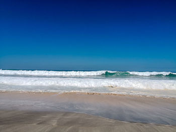 Scenic view of beach against clear blue sky