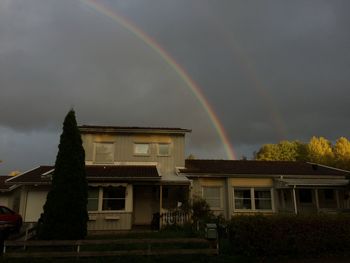 Low angle view of rainbow over building against sky
