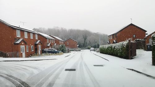 Road amidst buildings against sky during winter