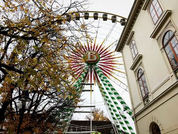 Low angle view of ferris wheel against buildings in city