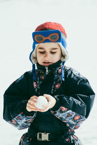 Boy in warm clothing making ball with snow