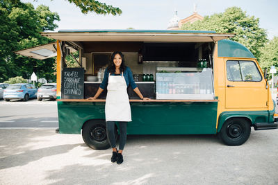 Portrait of smiling female owner standing against food truck