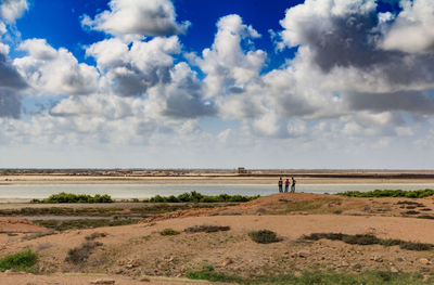 People on riverbank against sky