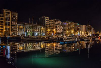 Illuminated boats moored at harbor against clear sky at night