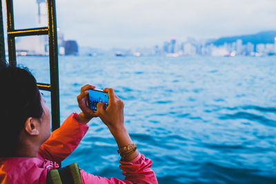 Man photographing with mobile phone in sea