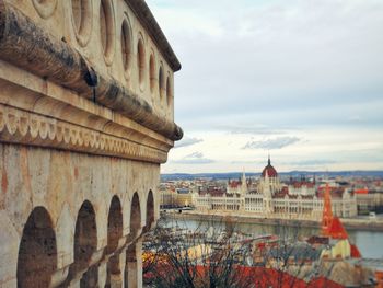 Old buildings in city against cloudy sky